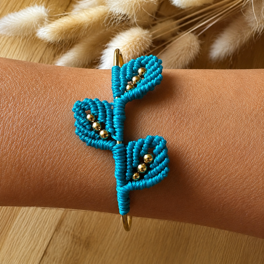 Bracelet jonc rigide en acier inoxydable avec tissage trois feuilles en micromacramé rose chamois et ses perles dorées.